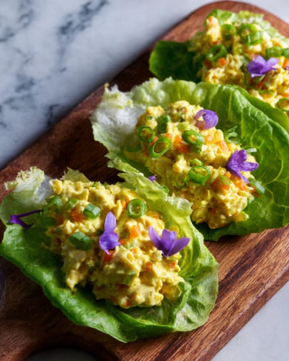 The image shows three lettuce cups arranged on a wooden board placed on a white marbled surface. Each lettuce cup is filled with a creamy yellow and orange mixture that looks like a salad, with small bits of vegetables visible. The green lettuce leaves have a fresh, crisp texture, and the salad is topped with thin bright purple flower petals and small green onion pieces. The wooden board contrasts nicely with the fresh colors of the food. Photo taken with an iphone --ar 4:5 --v 7