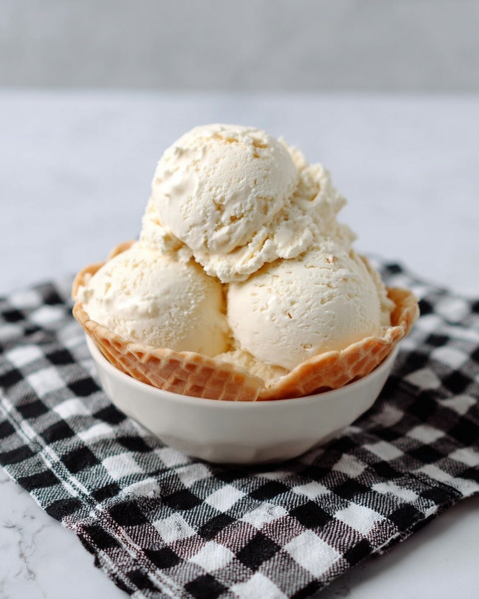 A white waffle bowl filled with four large scoops of creamy, off-white ice cream with a slightly rough texture and small chunks mixed in, resting on a black and white checkered cloth on a white marbled surface. The ice cream scoops are piled high, showing a soft, smooth, and slightly melting appearance. photo taken with an iphone --ar 4:5 --v 7