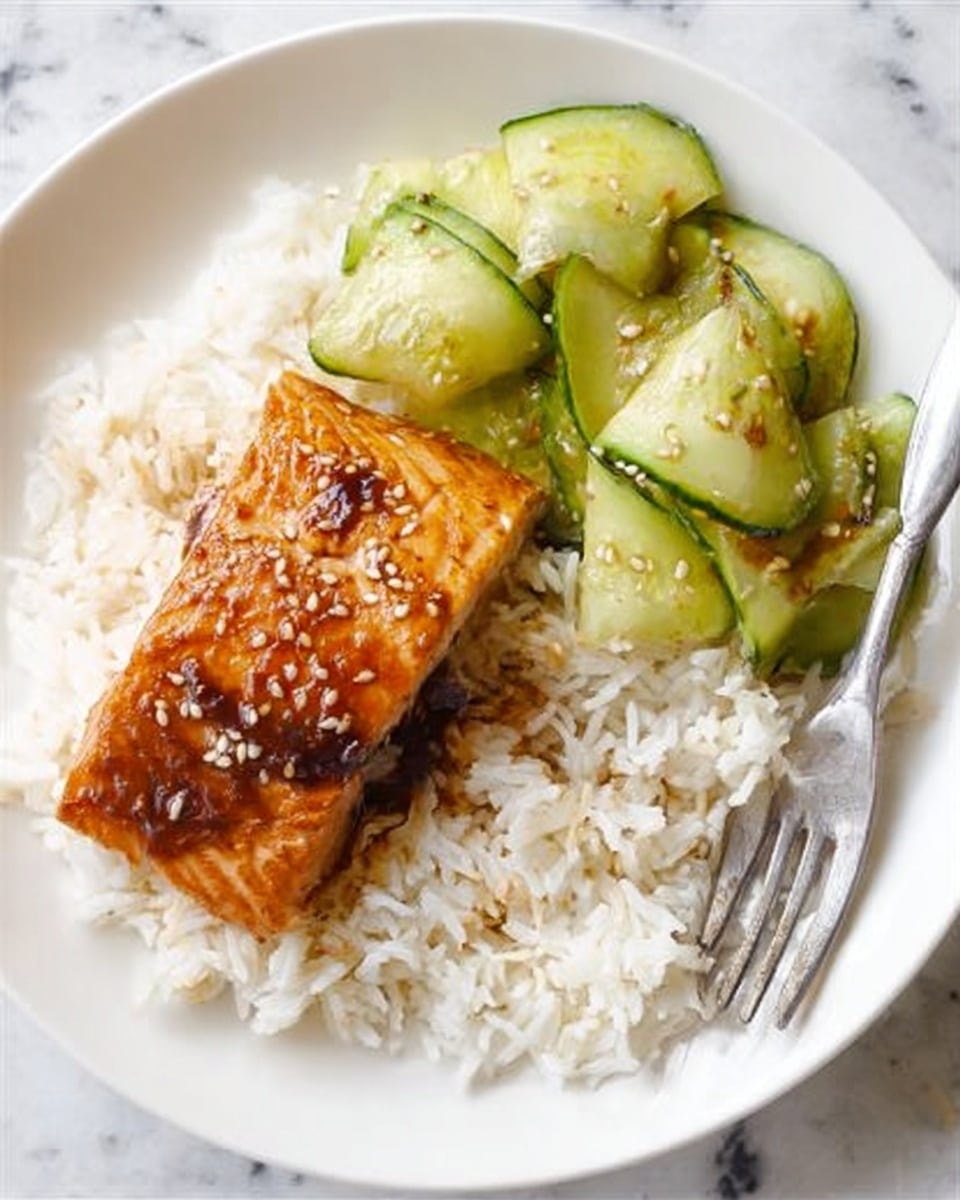 A white plate holds a simple, clean meal with three main parts: at the bottom is a layer of fluffy white rice with visible grains, on the right side a shiny silver fork rests on the plate edge, near the top is a portion of light green, thinly sliced cucumber ribbons with sesame seeds sprinkled on top, and in the center lies a rectangular piece of glazed salmon with a golden-brown surface, showing a shiny, slightly sticky texture from the sauce. The plate sits on a white marbled surface. photo taken with an iphone --ar 4:5 --v 7