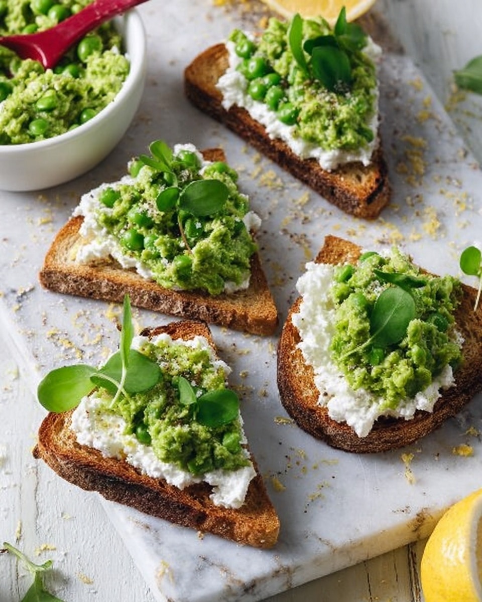 The image shows four open-faced toast triangles on a white marbled surface. Each toast slice has a base of thick, crusty rustic bread with a golden-brown texture and air pockets visible in the crumb. On top of the bread is a thick, white creamy layer, likely cheese, spread evenly. Over the white layer, there is a chunky, bright green spread that looks like mashed peas or avocado. Each toast is garnished with fresh green leaves, adding a fresh, leafy texture and color contrast. In the background, there is a white bowl with the same green spread, a halved lemon with some zest on the surface, and a red spoon resting inside the bowl. The overall scene is bright and fresh, with natural light highlighting the textures and colors. photo taken with an iphone --ar 4:5 --v 7
