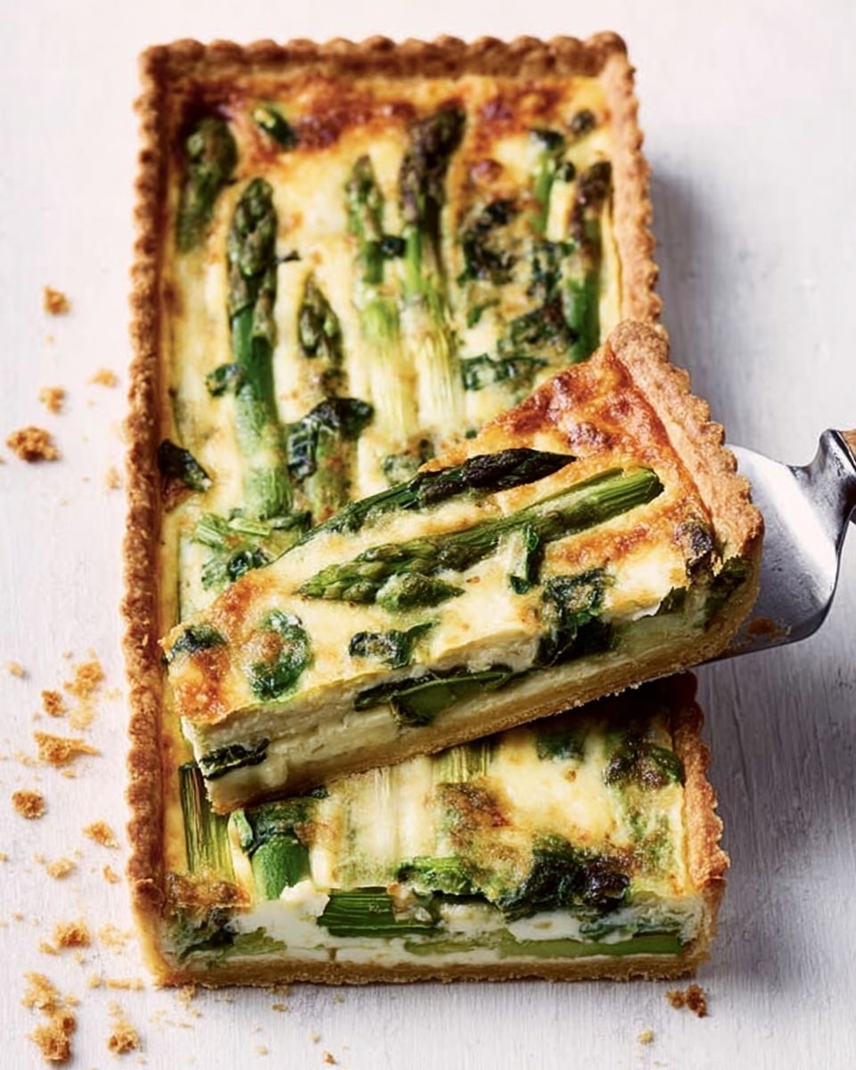 The image shows a rectangular tart with a golden brown, crispy crust that is thick and well-baked. Inside, the tart has a creamy light-yellow filling with green asparagus pieces arranged in a neat layer, showing their tips naturally shaped and slightly darker green leaves scattered on top. The filling looks smooth with toasted cheese melted over it, having small browned spots. A silver spatula is lifting a triangular slice from the tart, revealing the same layers inside. The dish sits on a white marbled surface. Photo taken with an iphone --ar 4:5 --v 7