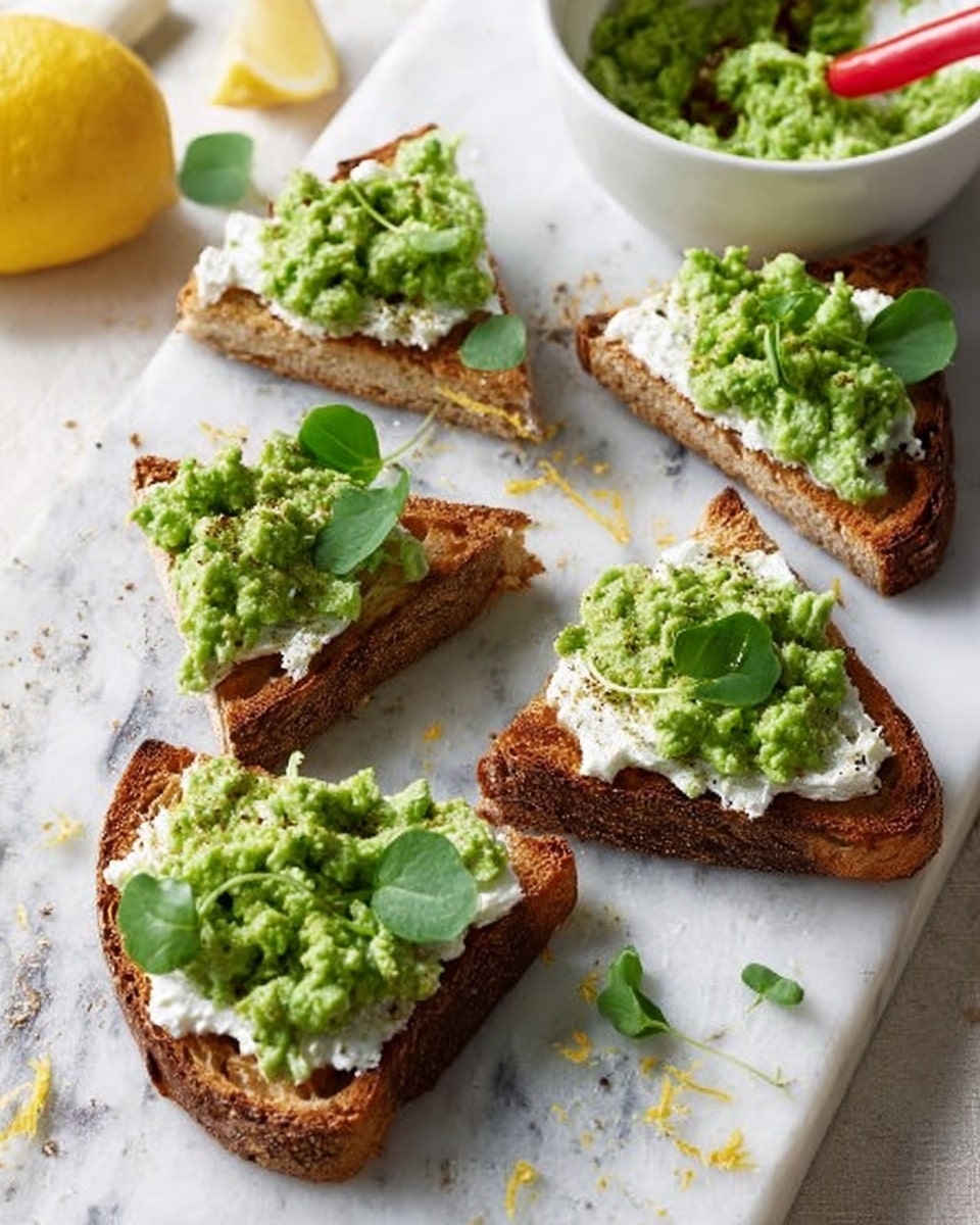 The image shows four triangular slices of toasted brown bread arranged on a white marbled surface. Each slice has three layers: the bottom layer is the textured, crisp toast with visible air holes; the middle layer is a thick spread of white creamy cheese evenly covering the toast; the top layer is a chunky green avocado mash placed in a small pile in the center. On top of each slice, there are small fresh green leaves for garnish. To the left, there is a halved lemon and some lemon zest, and in the background, part of a white bowl with additional avocado mash and a red spoon is visible. photo taken with an iphone --ar 4:5 --v 7