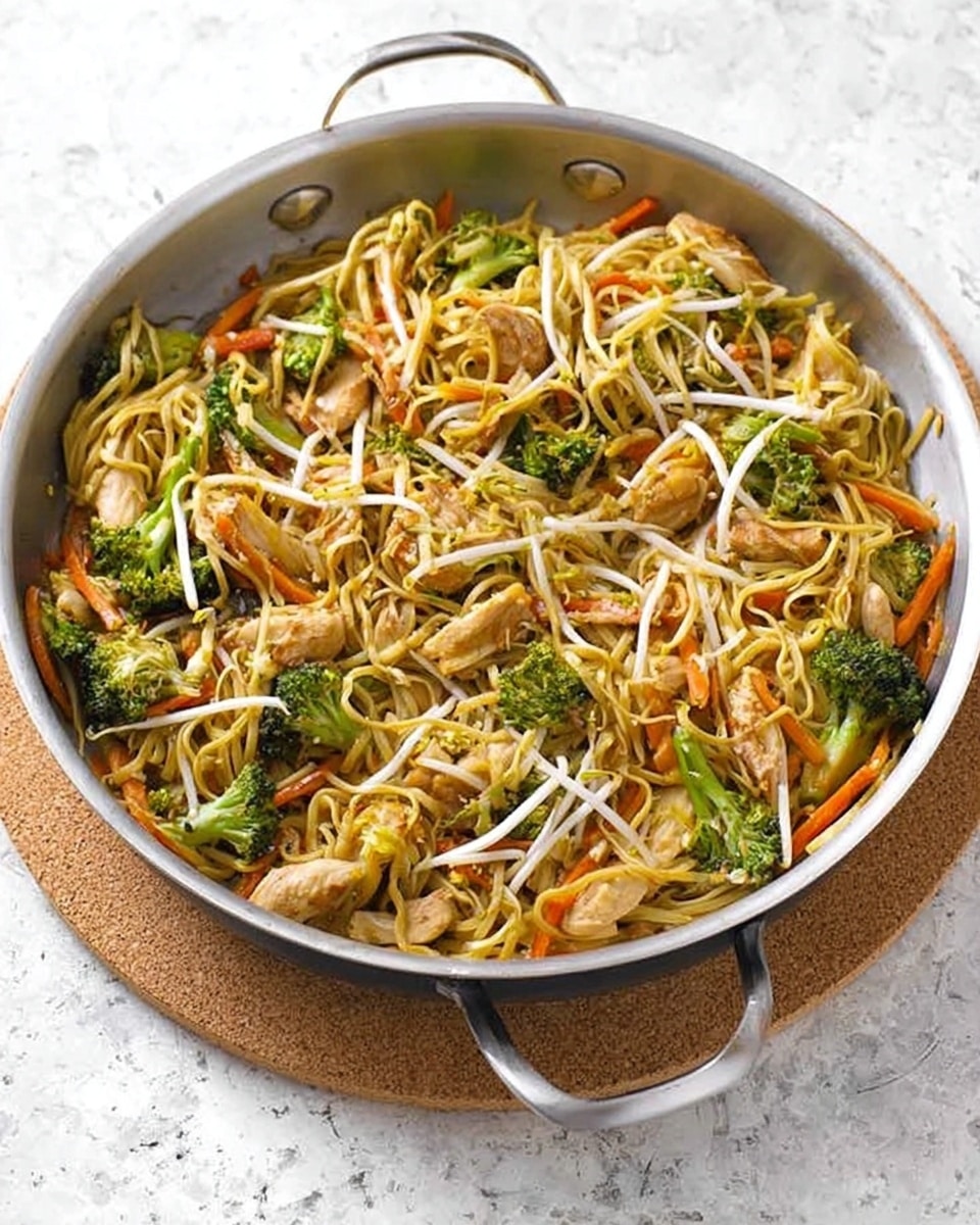 A large metal pan holds a stir fry dish with three main layers: at the bottom is a mix of thin yellow noodles tangled together, on top of that are evenly scattered bright green broccoli florets and thin orange carrot sticks, and resting mostly on the noodles are several brown glazed pieces of chicken. Thin white bean sprouts are spread on top for texture. The pan sits on a cork mat against a white marbled background, with a pair of chopsticks in the back. Photo taken with an iphone --ar 4:5 --v 7