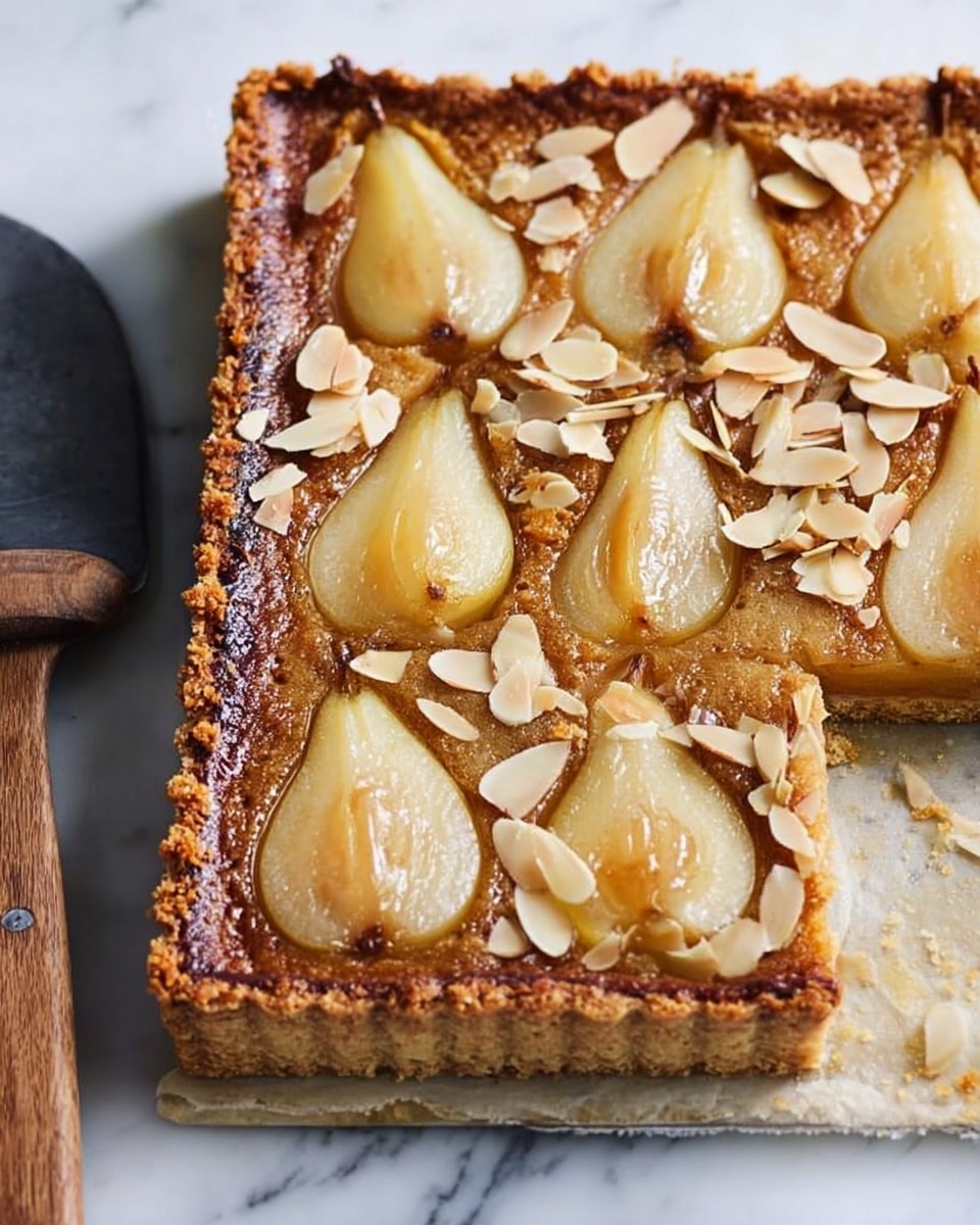A square tart with a golden-brown crust has a textured, slightly rough surface. Inside the crust, there are four halved pears embedded in a light brown filling that looks moist and smooth. Each pear half is pale yellow with a stem intact, arranged evenly with one in each corner. Toasted almond slices are scattered on top, adding a crunchy texture and a light tan color contrast. The tart rests on a white surface with a wooden serving spatula beside it. Photo taken with an iphone --ar 4:5 --v 7