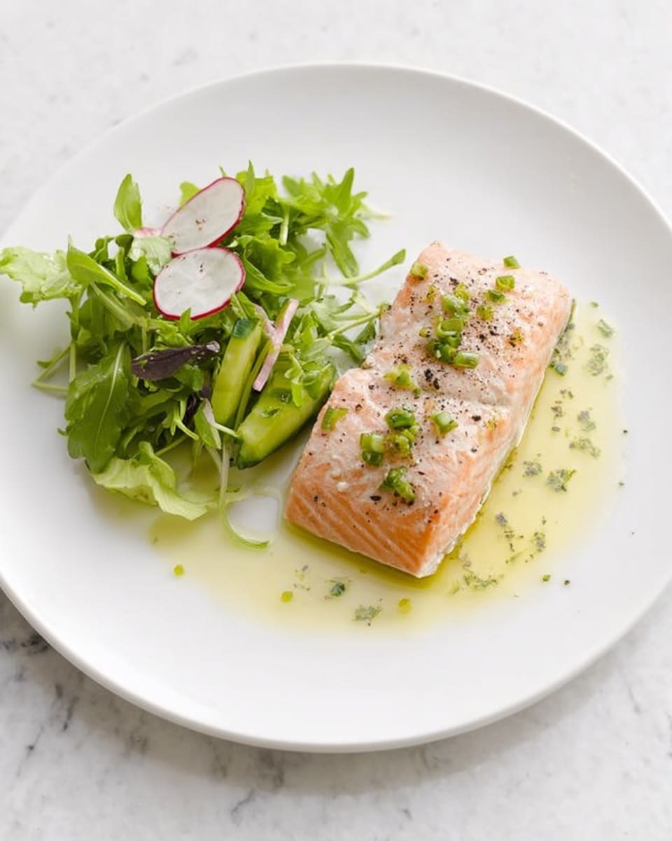 A white plate with a piece of cooked salmon placed slightly off-center, the salmon is light orange-pink with a moist texture and topped with small green herb pieces and a sprinkle of black pepper. To the left side of the salmon is a small pile of fresh green mixed salad leaves including arugula and thin slices of radish and cucumber, adding a mix of dark green, light green, and pale pink colors. There is a drizzle of light yellow-green sauce beneath the salmon and extending slightly to its right, with small herb bits in it. The plate sits on a white marbled surface. Photo taken with an iphone --ar 4:5 --v 7