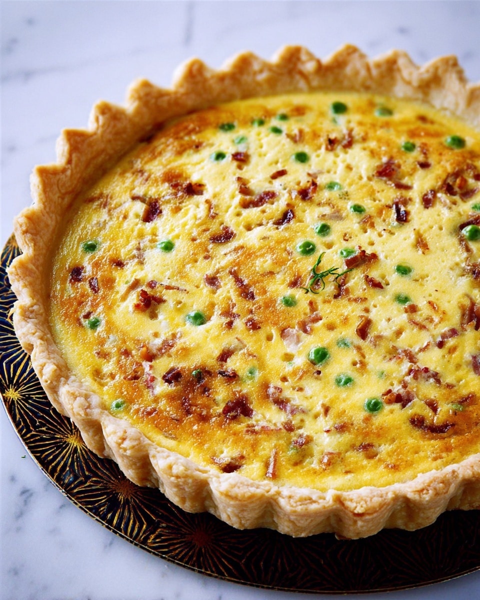 A round quiche with a golden crust that is thick and crimped around the edges, holding a creamy yellow egg filling. The filling is mixed with small green peas, light brown bits of bacon, and soft cooked onions scattered evenly across the surface, which has a slightly browned and bubbly texture. The quiche sits on a dark patterned baking tray, placed on a white marbled texture surface. Photo taken with an iphone --ar 4:5 --v 7