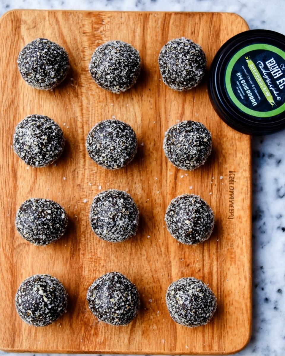 The image shows fourteen small round balls placed in a grid on a wooden board with a white marbled background. Each ball is covered in a coarse black and white coating, giving them a textured, rough look that resembles crushed seeds or nuts. The balls are arranged neatly in four rows, with some uneven spacing. On the right side of the board, there is a round black container lid with green and white text. The overall color palette is natural and earthy, focusing on the contrast between the dark balls and the lighter wooden surface. Photo taken with an iphone --ar 4:5 --v 7
