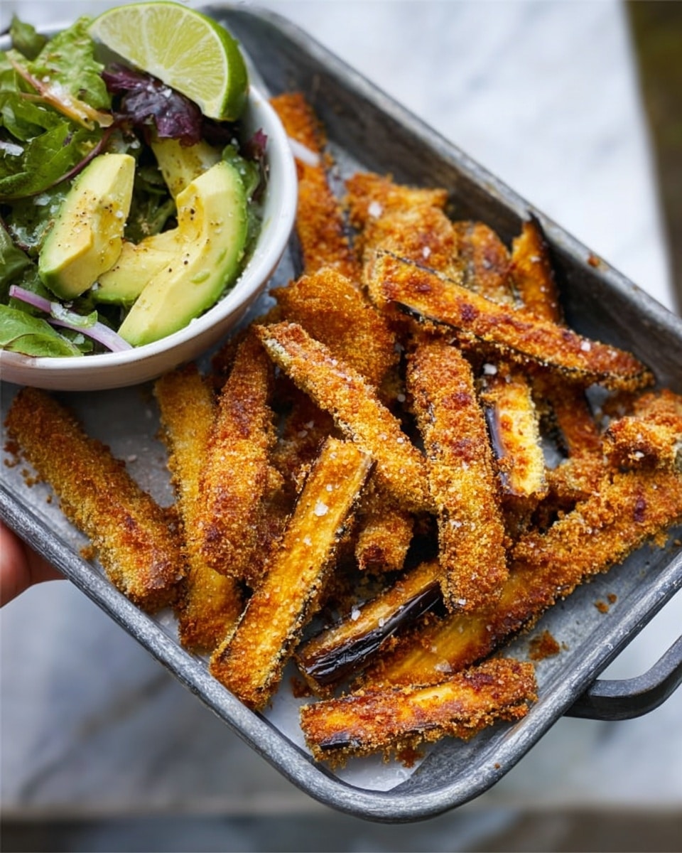 The image shows a metal tray filled with crispy, golden brown fried eggplant sticks that have a crumbly texture and some darker edges, showing they are well cooked. On the left side of the tray, there is a white bowl containing a fresh green salad with avocado slices, lime wedge, and some other mixed green vegetables. The tray is placed on a white marbled surface, creating a clean and bright background. A woman's hand is holding the bowl slightly off to the side, with the focus on the food. photo taken with an iphone --ar 4:5 --v 7
