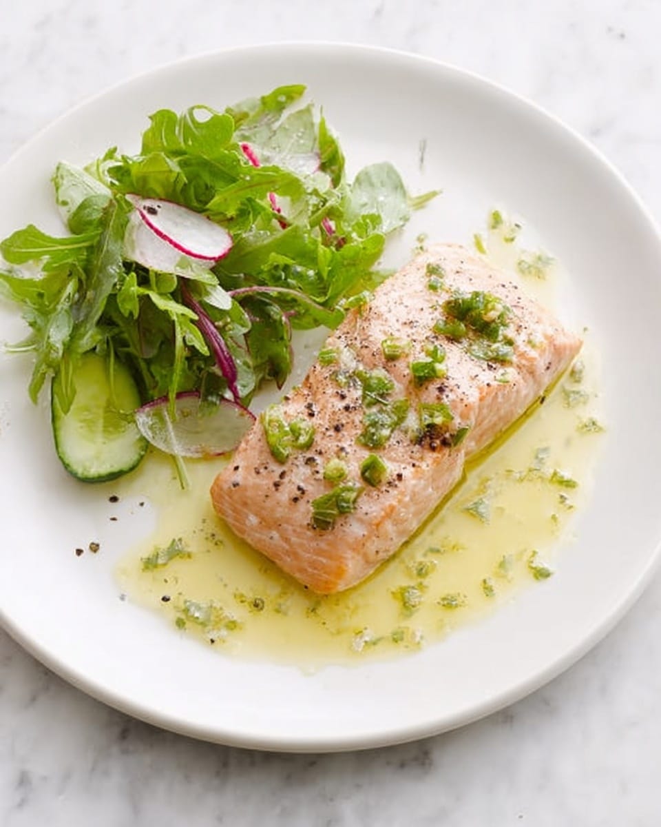 A white plate on a white marbled surface holds two pieces of cooked salmon placed side by side as the bottom layer, light pink with a slightly glazed texture and small pepper flakes sprinkled on top; to the right and underneath the salmon is a glossy green sauce spread thinly with a few small chopped green herbs scattered over it; on the left side of the plate, a fresh salad layer includes mixed green leafy vegetables with thin slices of white radish and zucchini ribbons for a contrast of crisp textures and light colors; the overall presentation is clean and simple, with a gentle mix of soft and fresh elements. photo taken with an iphone --ar 4:5 --v 7