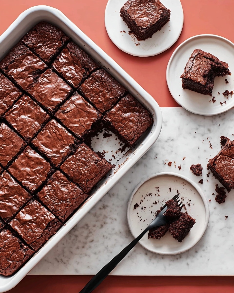 The image shows a white square baking dish filled with 16 neatly cut brownies, arranged in a 4 by 4 grid, with one piece missing from the bottom left corner, revealing a moist, dense inside texture. A knife with a wooden handle rests on the top edge of the dish. Around the baking dish, there are three pieces of brownies on three separate white plates: one on a plain white plate, another on a green textured plate with a black fork beside it, and a third on a dark plate with a fork on it. The surface beneath everything is a white marbled texture. The brownies have a rich, dark chocolate color with a slightly cracked, shiny top crust. photo taken with an iphone --ar 4:5 --v 7