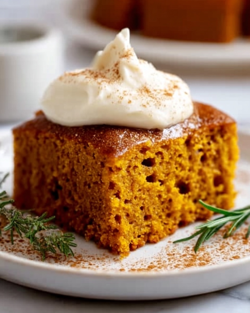 A square piece of moist pumpkin cake with a light brown color sits on a white plate with a sprinkle of cinnamon around it. On top of the cake, there is a dollop of creamy white frosting. Next to the cake, there is a small sprig of green rosemary. The plate rests on a white marbled surface, giving a clean and fresh look. photo taken with an iphone --ar 4:5 --v 7