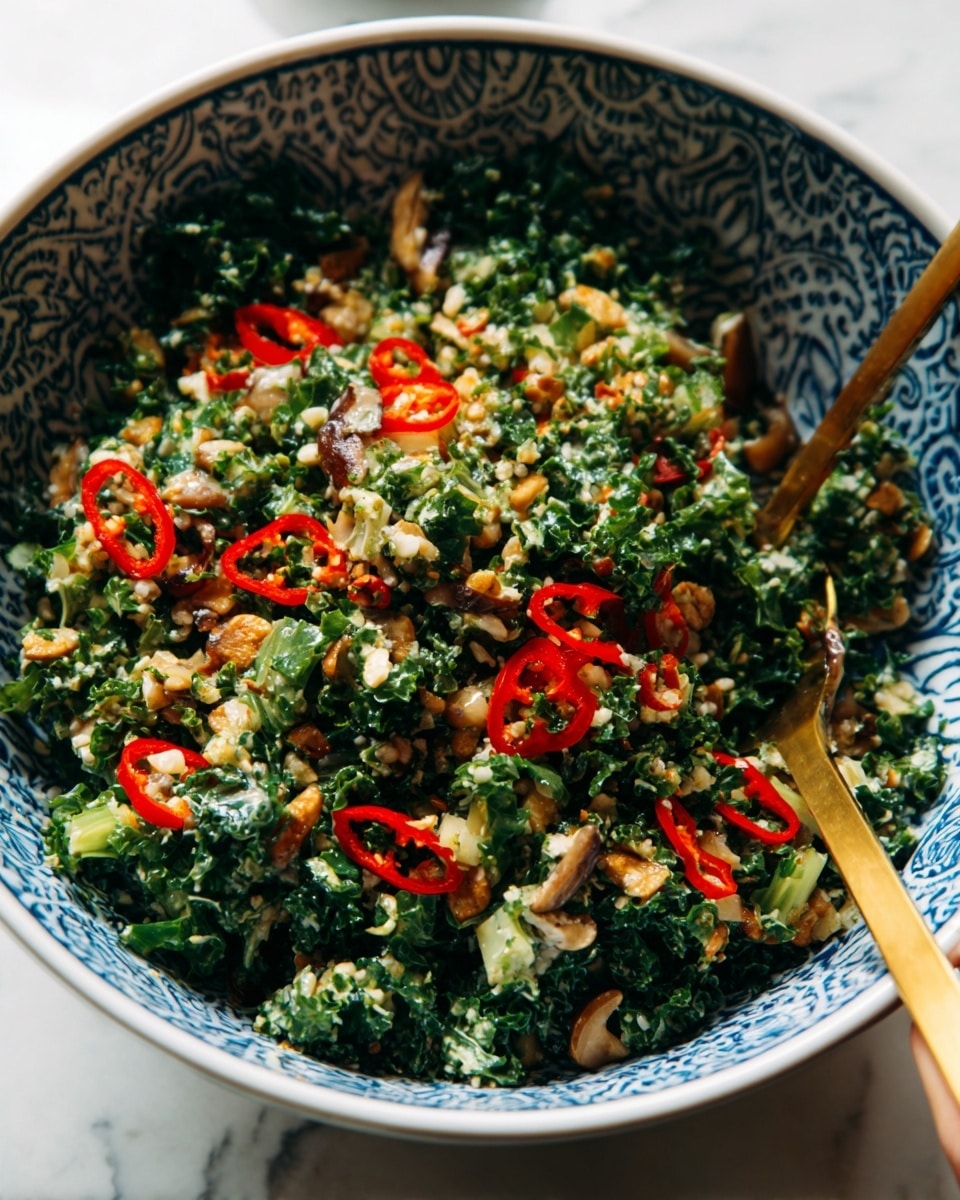 A white bowl filled with a colorful salad featuring multiple layers and textures. At the bottom, finely chopped dark green kale leaves create a leafy, rough texture. Scattered throughout are thin slices of bright red chili peppers adding pops of bold color. Mixed in are pieces of light green celery and bits of creamy white chopped nuts, giving a crunchy texture. The salad also has small white grains or seeds spread evenly, creating a speckled look. Near the edge, a metal fork with a gold handle rests inside the bowl. The bowl sits on a smooth white marbled surface. Photo taken with an iphone --ar 4:5 --v 7