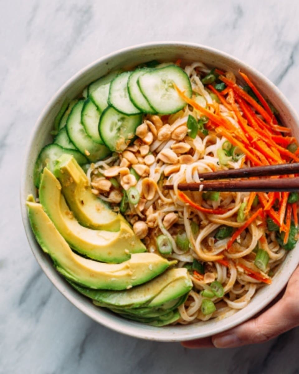 A white bowl filled with a colorful salad placed on a white marbled surface, featuring three main layers: the bottom layer consists of light-colored noodles with a smooth texture; on top, there are thinly sliced cucumber rounds arranged in a neat row on one side, displaying a fresh green color with visible seeds; beside the cucumber, vibrant red tomato slices add brightness, mixed with fresh green herbs sprinkled over; next to these, there are thick slices of creamy avocado showing a pale green color; scattered throughout the bowl are crunchy pine nuts adding texture and small bits of green jalapeño peppers for a touch of spice. A woman's hand is holding the bowl on the left side, and a gold fork is resting inside, partially submerged in the noodles. Photo taken with an iphone --ar 4:5 --v 7