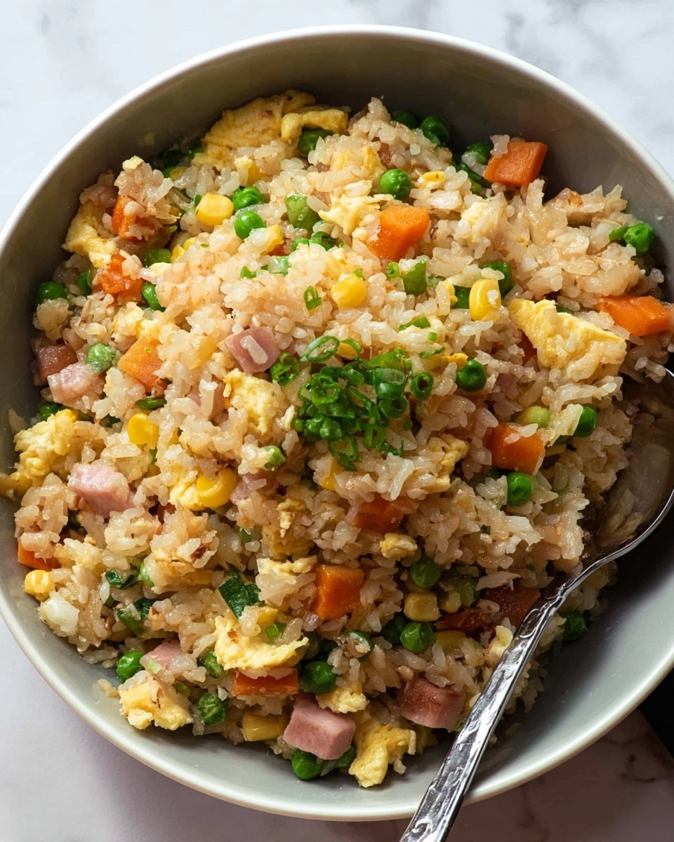 The image shows a close-up of a bowl filled with fried rice, placed on a white marbled surface. The fried rice has several layers mixed thoroughly: fluffy white and golden rice grains, bright yellow corn kernels, diced orange carrots, and green peas spread evenly throughout. Small pieces of light pink ham and soft, scrambled egg chunks add texture and color. There are also fresh green onion slices sprinkled on top, giving a fresh look. A spoon rests inside the bowl, partly visible on the right side. photo taken with an iphone --ar 4:5 --v 7