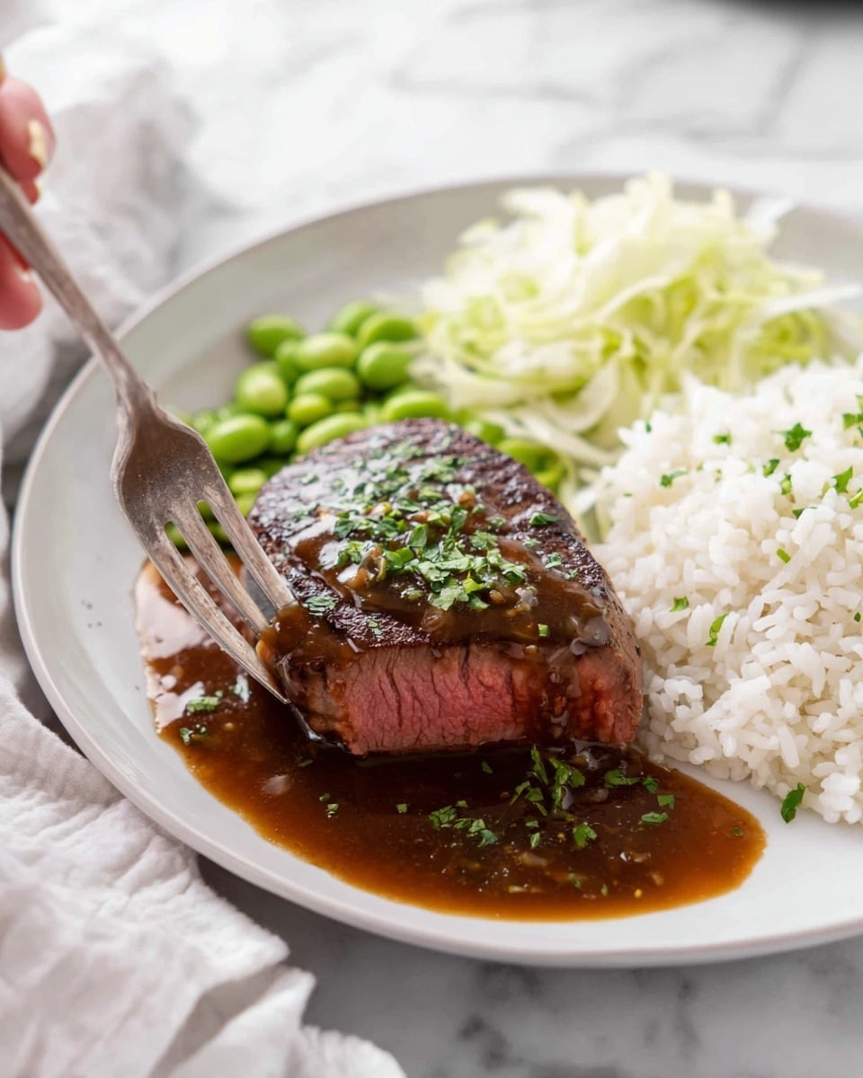 A white plate shows a piece of steak with a dark brown sauce on top and sprinkled with green herbs. The steak is cut to show a pink inside and sits in a pool of brown sauce with small herb bits spread around. To the right side of the steak, there is a pile of white rice mixed with some green soybeans and light-colored shredded cabbage behind it. A fork holds a small piece of steak in front of the main piece. The plate is on a white marbled surface with a soft white cloth nearby. Photo taken with an iphone --ar 4:5 --v 7