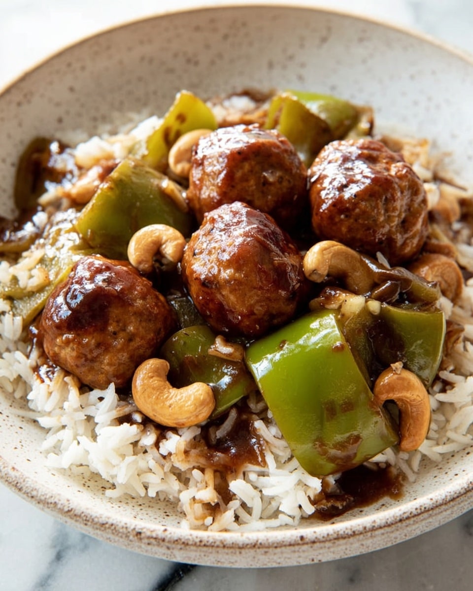 A white bowl holds a dish with three visible layers: the bottom layer is white steamed rice with separated grains, the middle layer consists of bright green bell pepper pieces and light brown cashew nuts scattered unevenly, and the top layer features several golden-brown meatballs with a shiny dark brown glaze. The dish sits on a white marbled surface. photo taken with an iphone --ar 4:5 --v 7