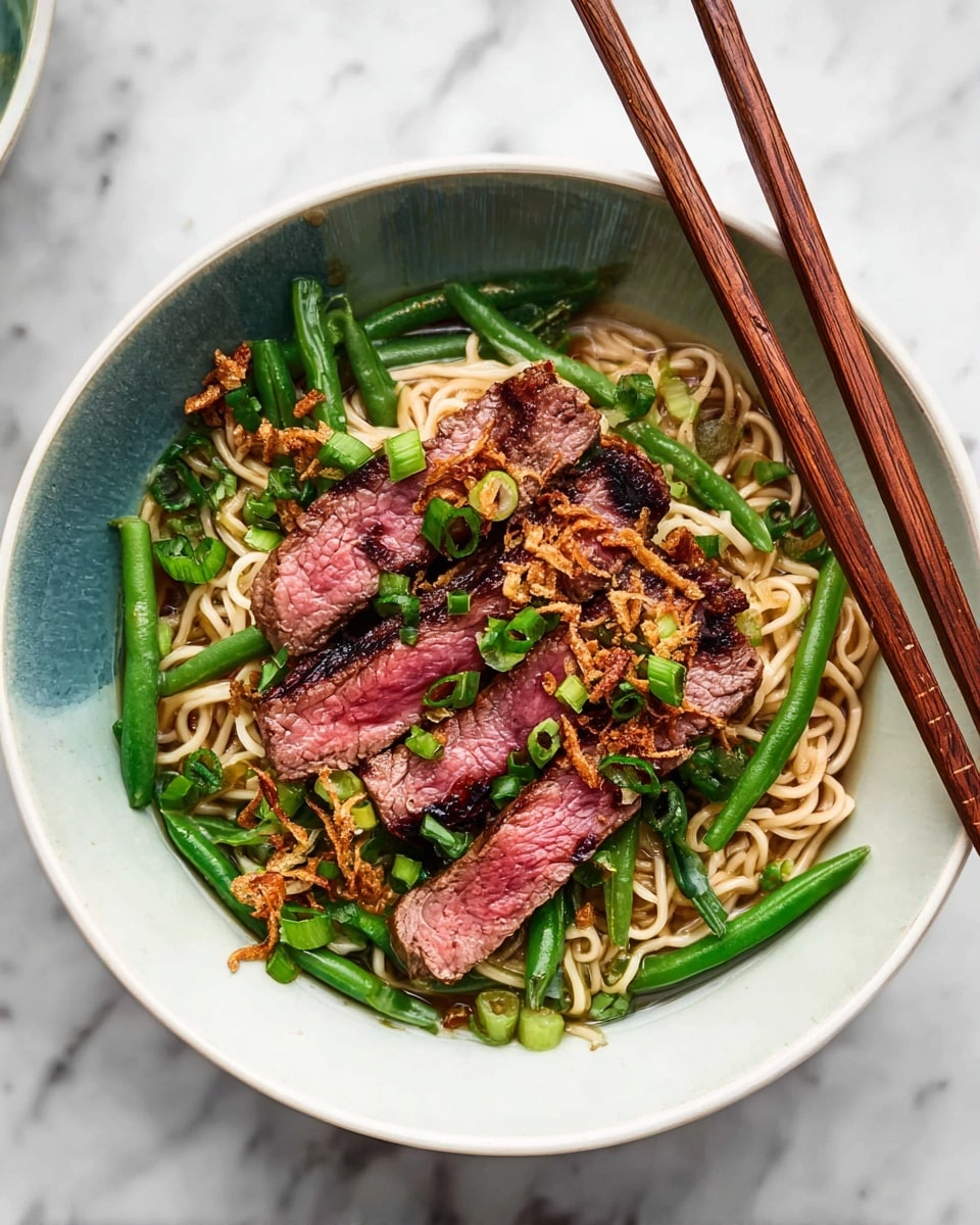 A bowl with a base layer of light beige noodles, topped with a layer of bright green long beans placed around the edges, then several slices of medium-rare steak with a pink center and charred edges arranged on top of the green beans. The steak is garnished with small rings of fresh green onions and crispy fried shallots scattered across the dish. A pair of light brown wooden chopsticks rests on the bowl's edge, all set on a white marbled surface. photo taken with an iphone --ar 4:5 --v 7